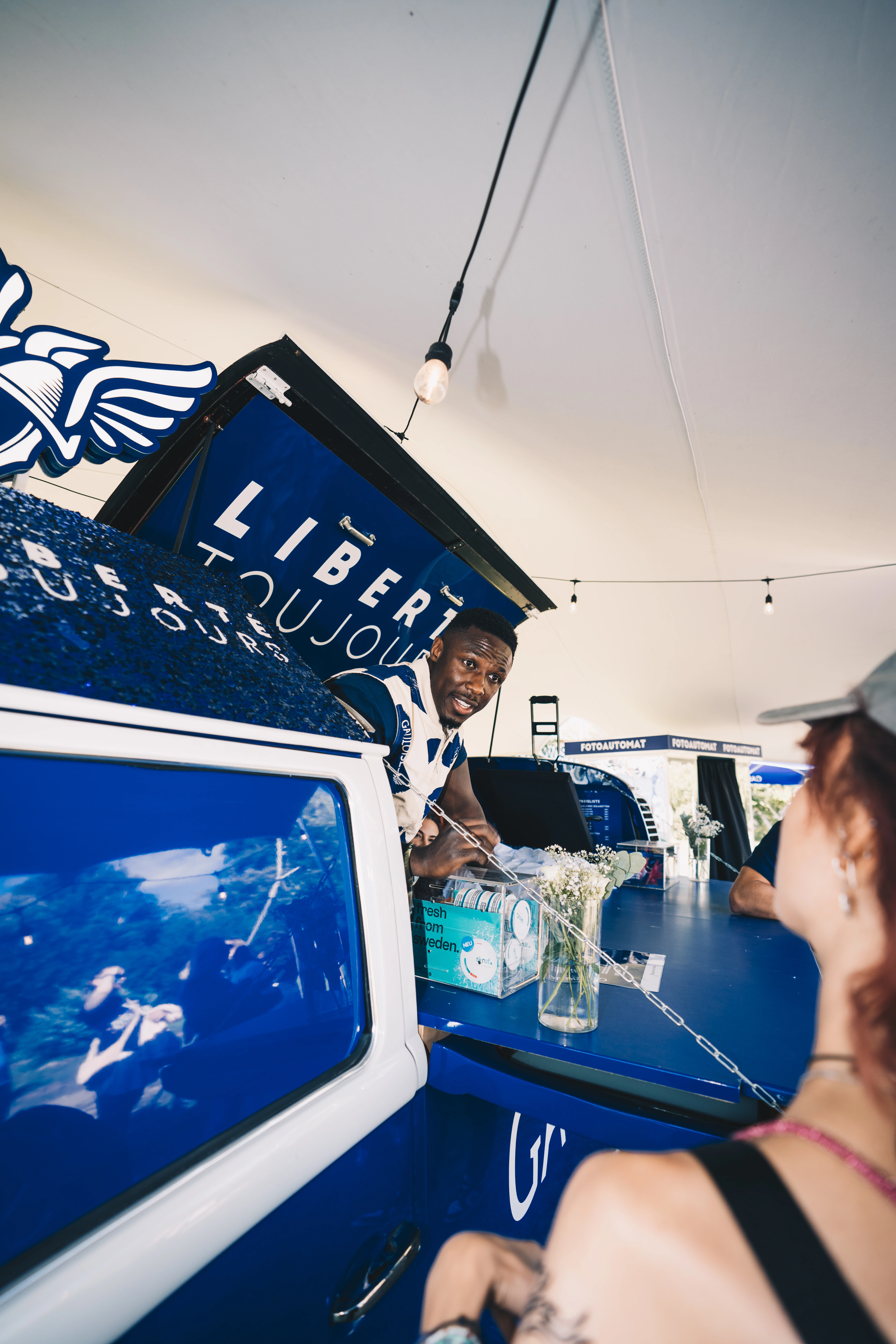 Ein Bild einer Employer Branding Festival Aktivierung eines Kunden der Employer Branding Agentur straling. Zu sehen ist eine blauer Gauloises Bus mit einem Mitarbeiter. 