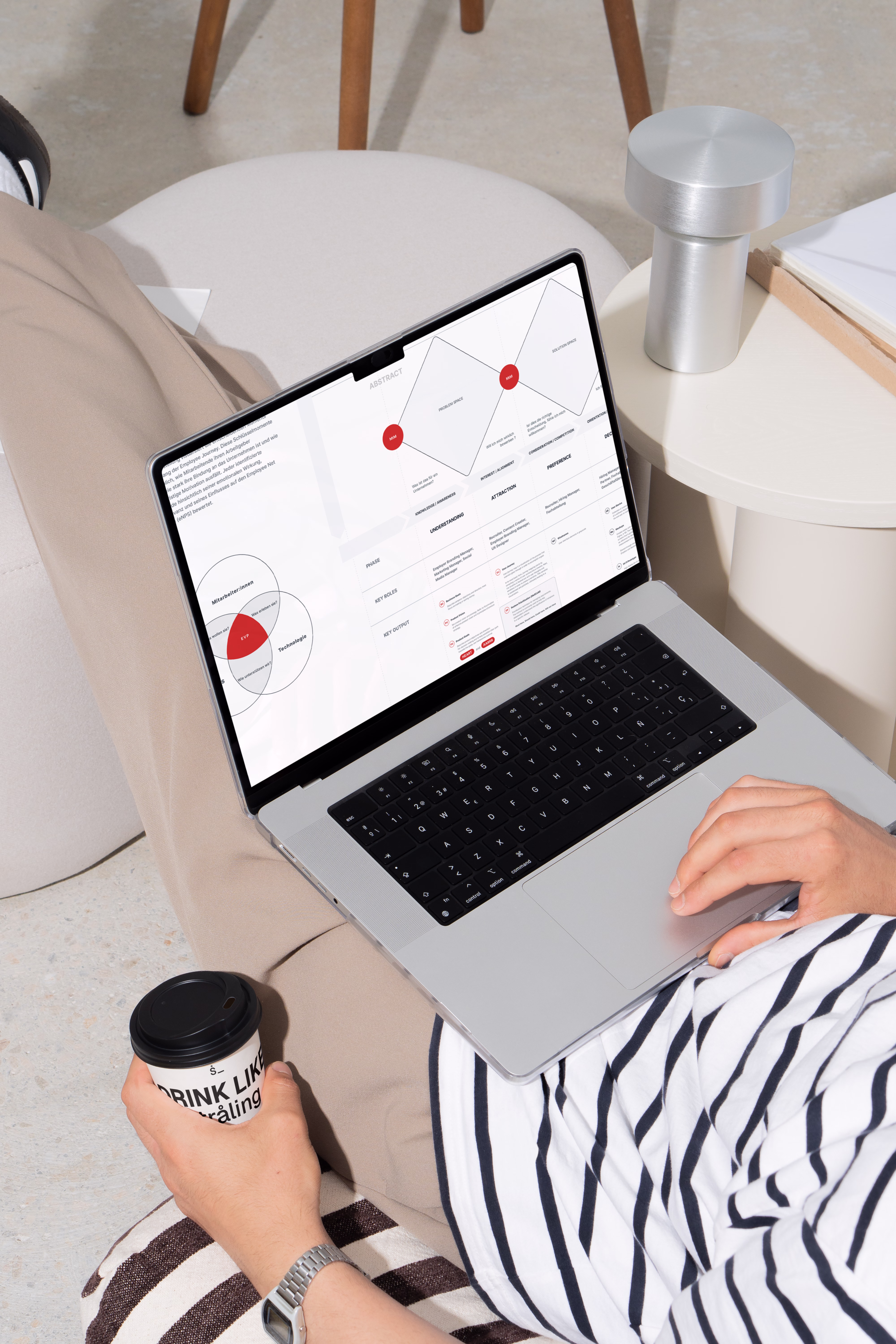 Ein Senior Employer Branding Consultant der award winning employer branding agentur straling, mit einem laptop auf dem bein, dessen Bildschirm eine optimierte candidate und employee experience journey zeigt, die straling für einen kunden entwickelt hat.