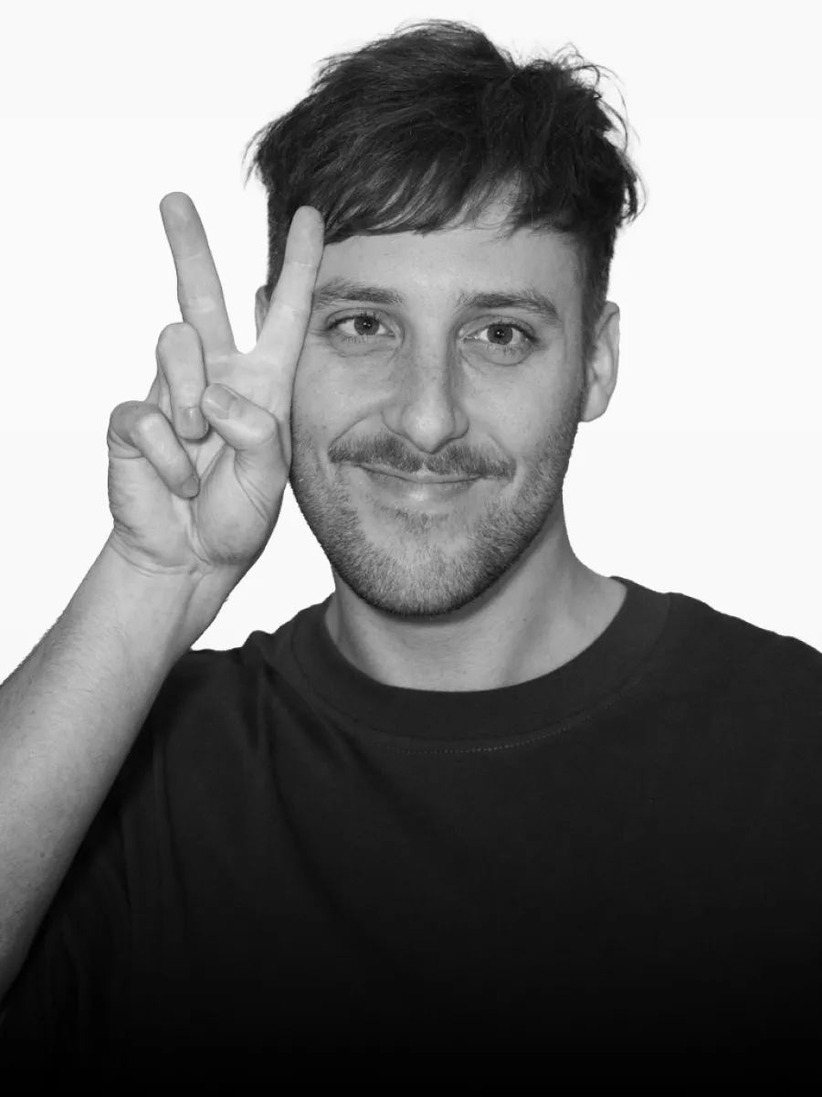 Porträtfoto von Lucas Böse, der lächelnd ein Peace-Zeichen neben seinem Gesicht zeigt.