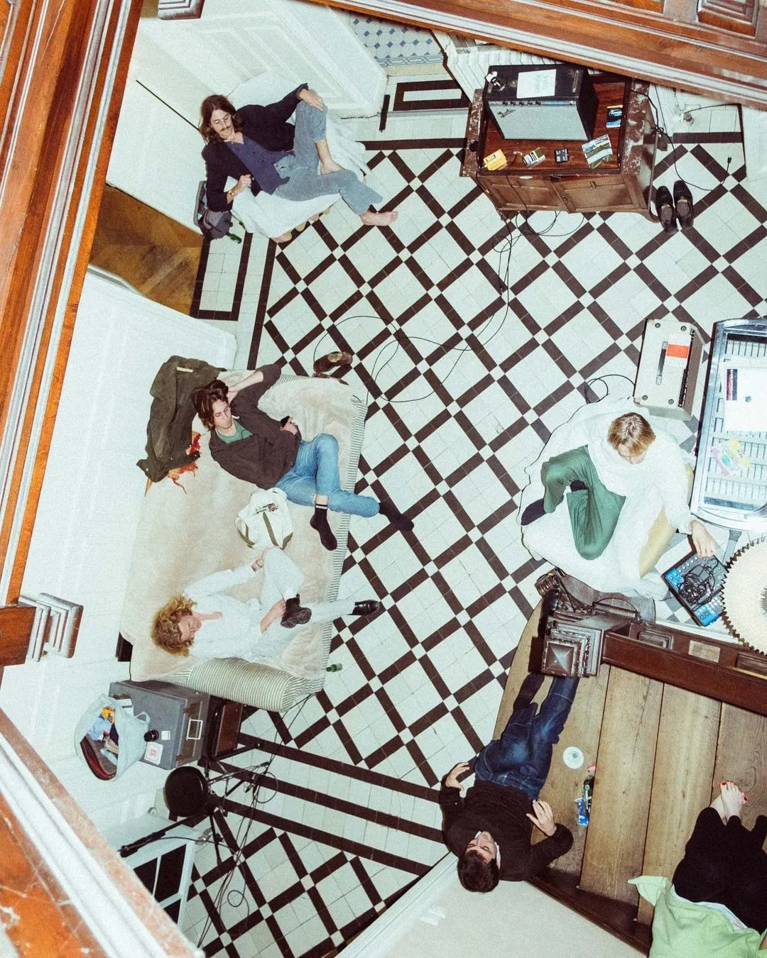 Bild für produktive Arbeit: mehrere Kolleg:innen kollaborieren entspannt im Studio, auf Sofa und Boden, Technik und Notizen sichtbar – effiziente Teamarbeit jenseits des Schreibtischs.