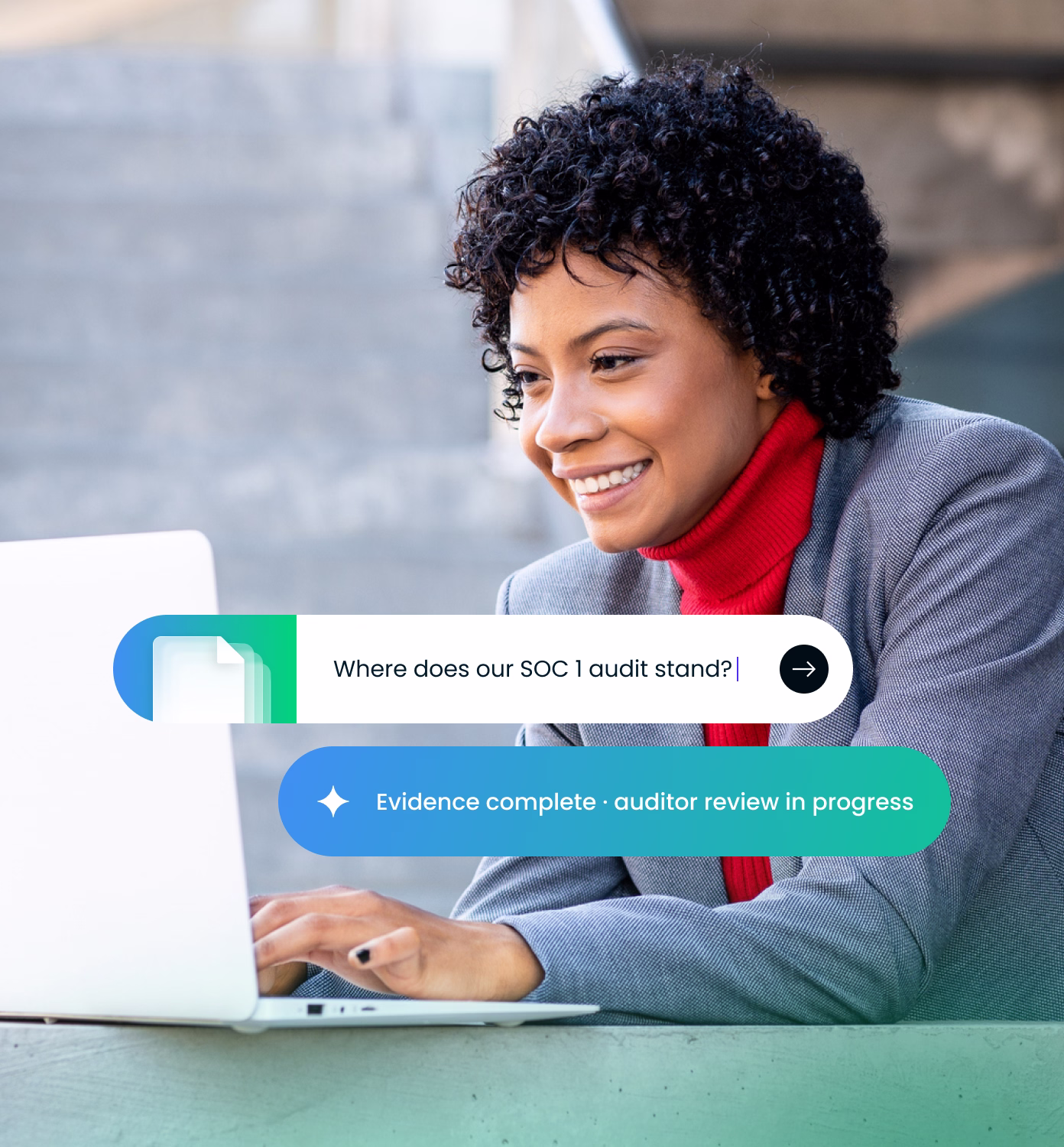 Smiling woman with curly hair wearing a gray blazer and red turtleneck, working on a laptop outdoors, with on-screen text prompts about SOC 1 audit status and evidence completion.
