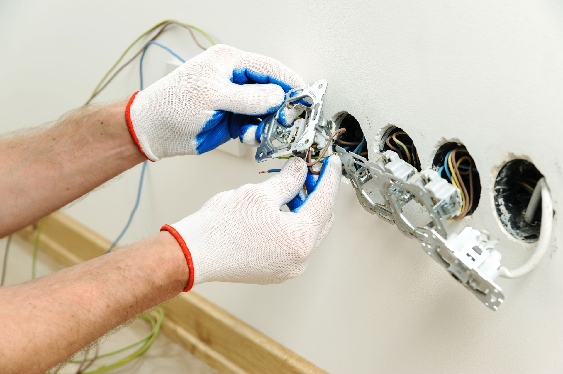 Electrician installing electrical wiring and outlets in a wall.