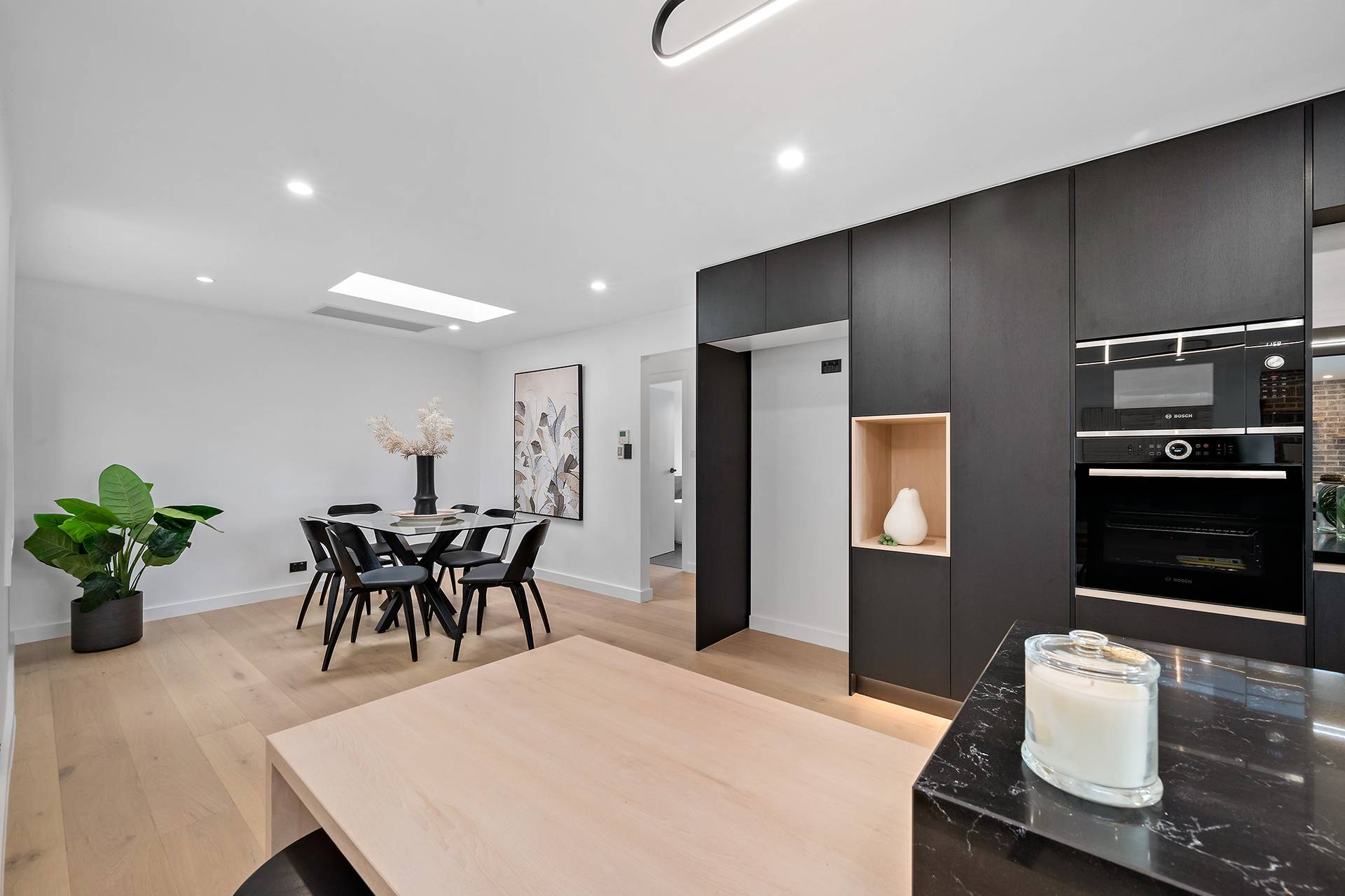 Modern dining room with black cabinetry, sleek furniture, and decorative elements, featuring a minimalist aesthetic.