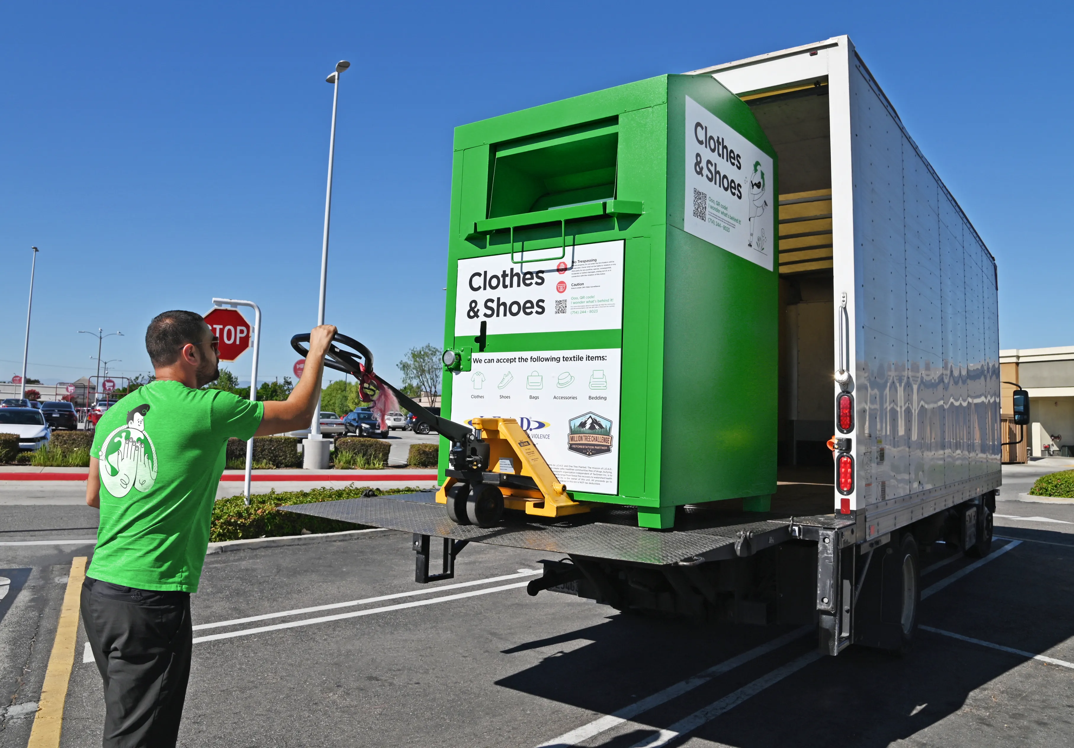 Green Team employee loading a clothing collection bin onto a truck for textile recycling in the USA.