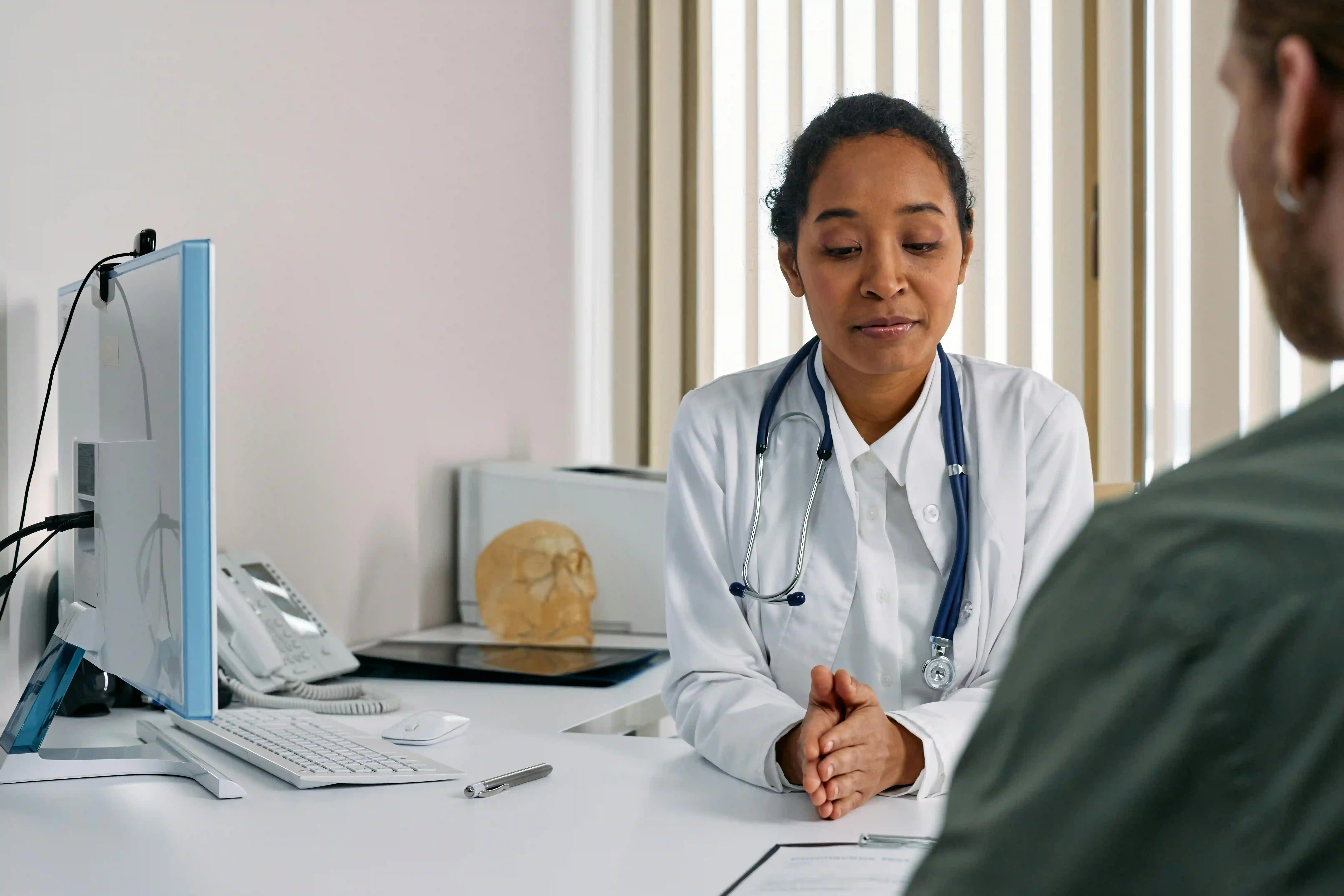 Female doctor in consultation with a patient, wearing a stethoscope in a medical office.