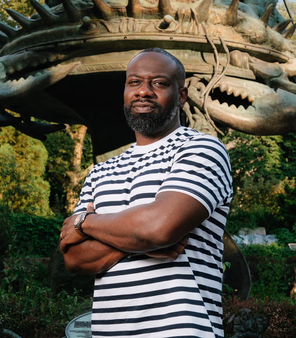 Lenny Bradley posing in front of dragon sculpture outdoors.