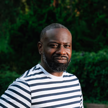 Close-up portrait of Lenny Bradley in park wearing striped shirt.