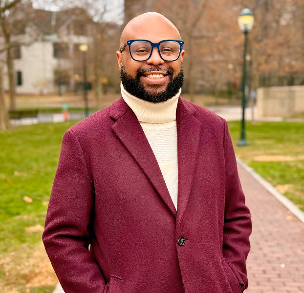 Desmond Upton Patton outdoors in burgundy coat, advancing trauma-informed research and digital empathy.