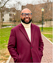 Desmond Upton Patton outdoors in burgundy coat, advancing trauma-informed research and digital empathy.