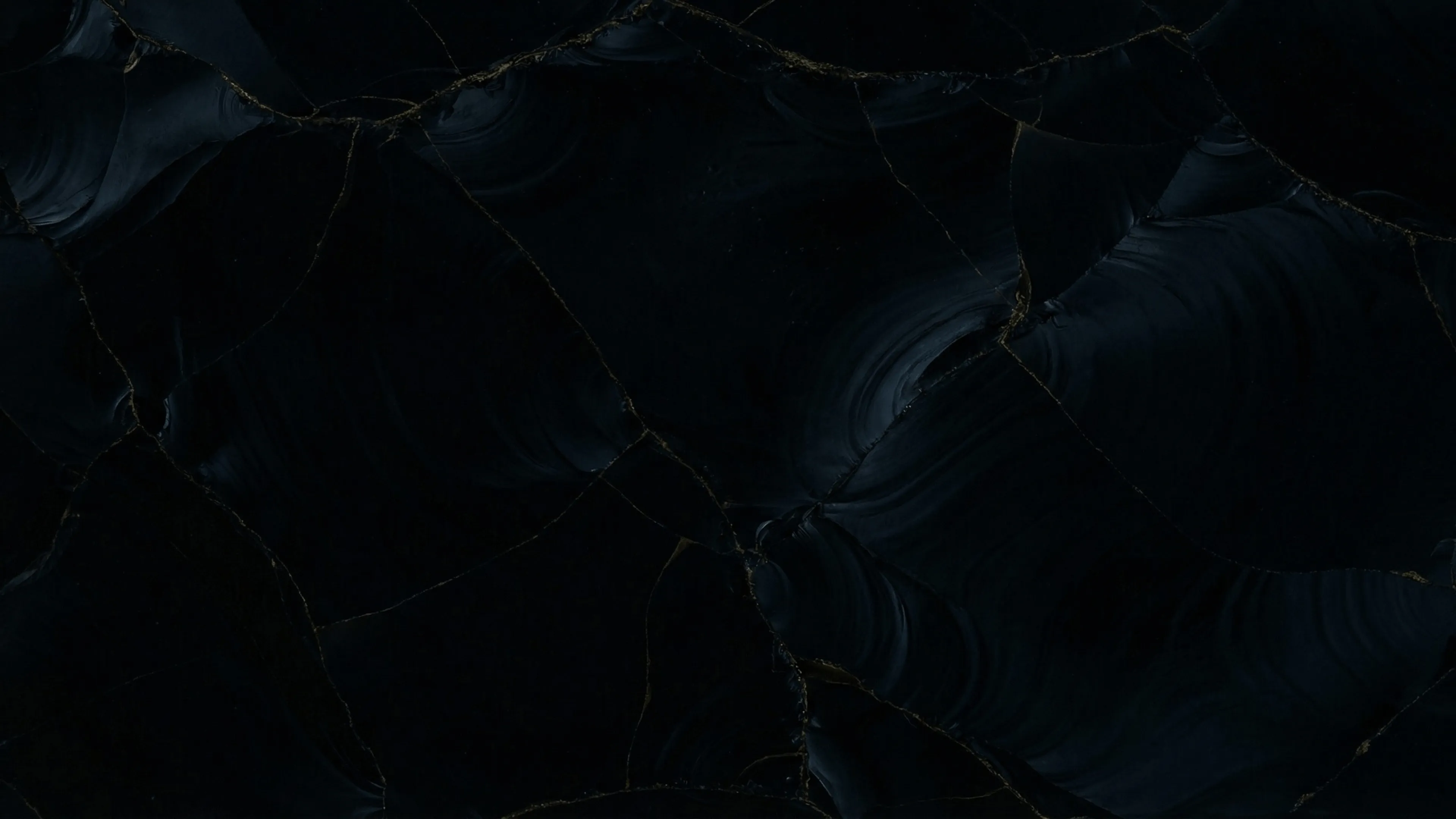 Dunkler Obsidianstein mit schwarzen und dunkelgrauen Strukturen und feinen goldenen Aderungen.