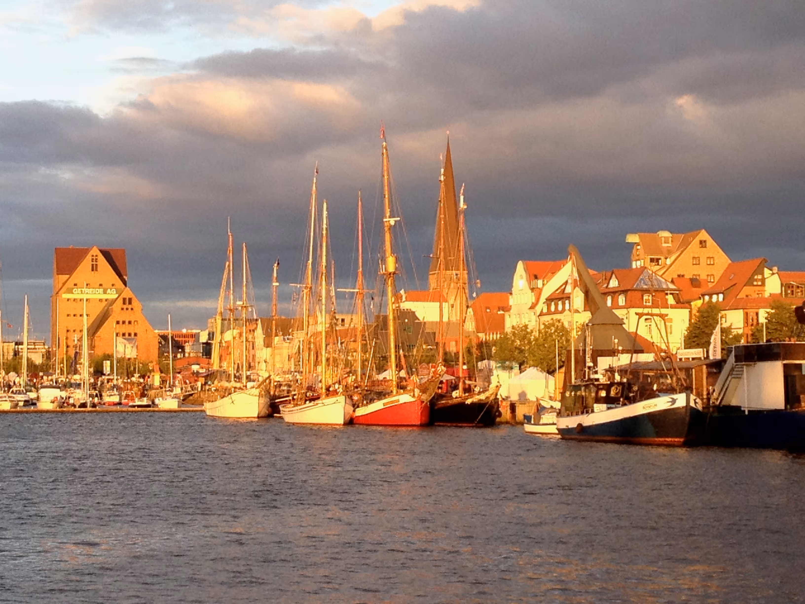 Segelschiffe liegen n der Abendsonne - eub Bild aus dem Stadthafen von Rostocl während der Hansesail