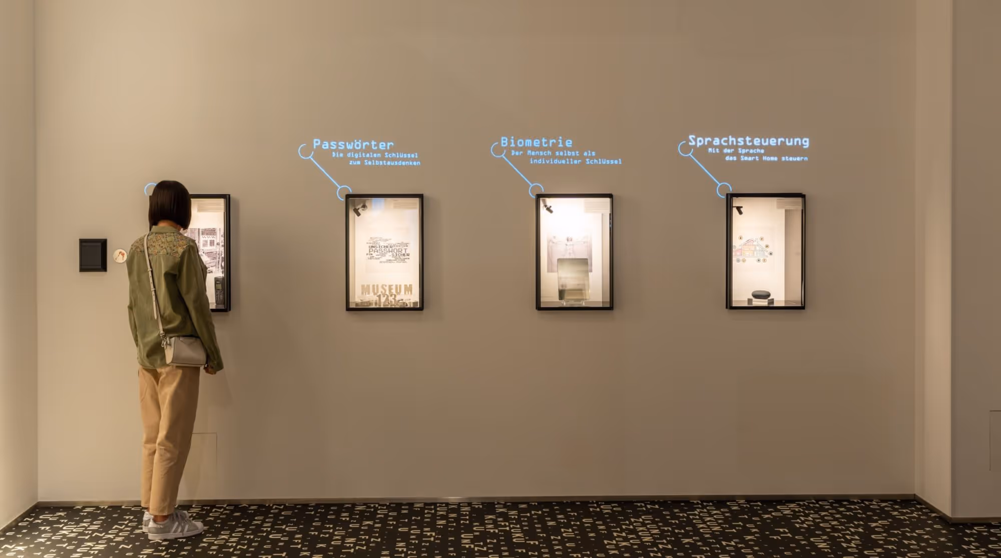 Eine Frau guckt interessiert in eine Vitrine des Museums, daneben sind weitere Vitrinen zu sehen. 