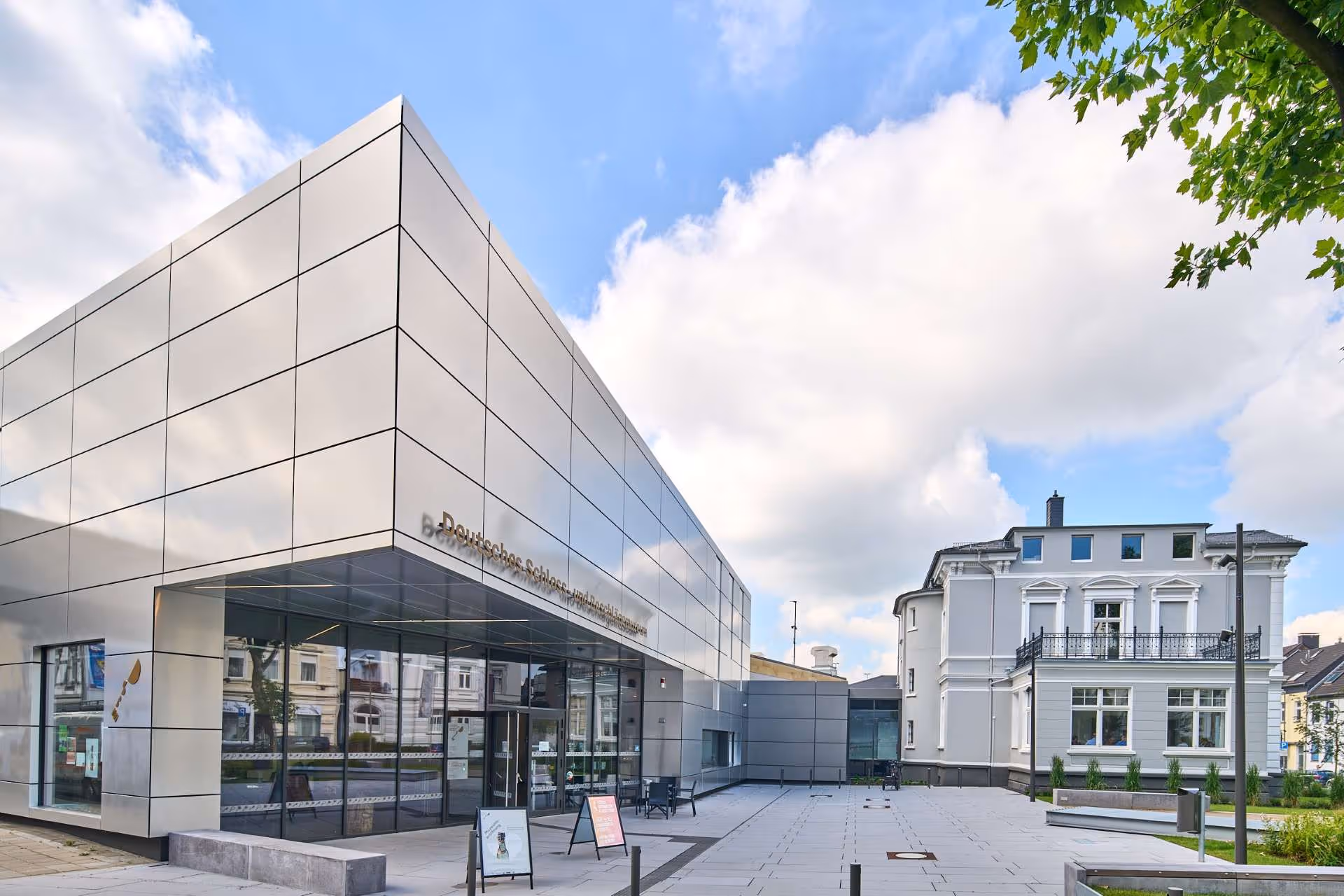 Ein Panoramafoto des Museums, das Metallplatten an der Fassade hat, und der gründerzeitlichen Villa Herminghaus daneben.