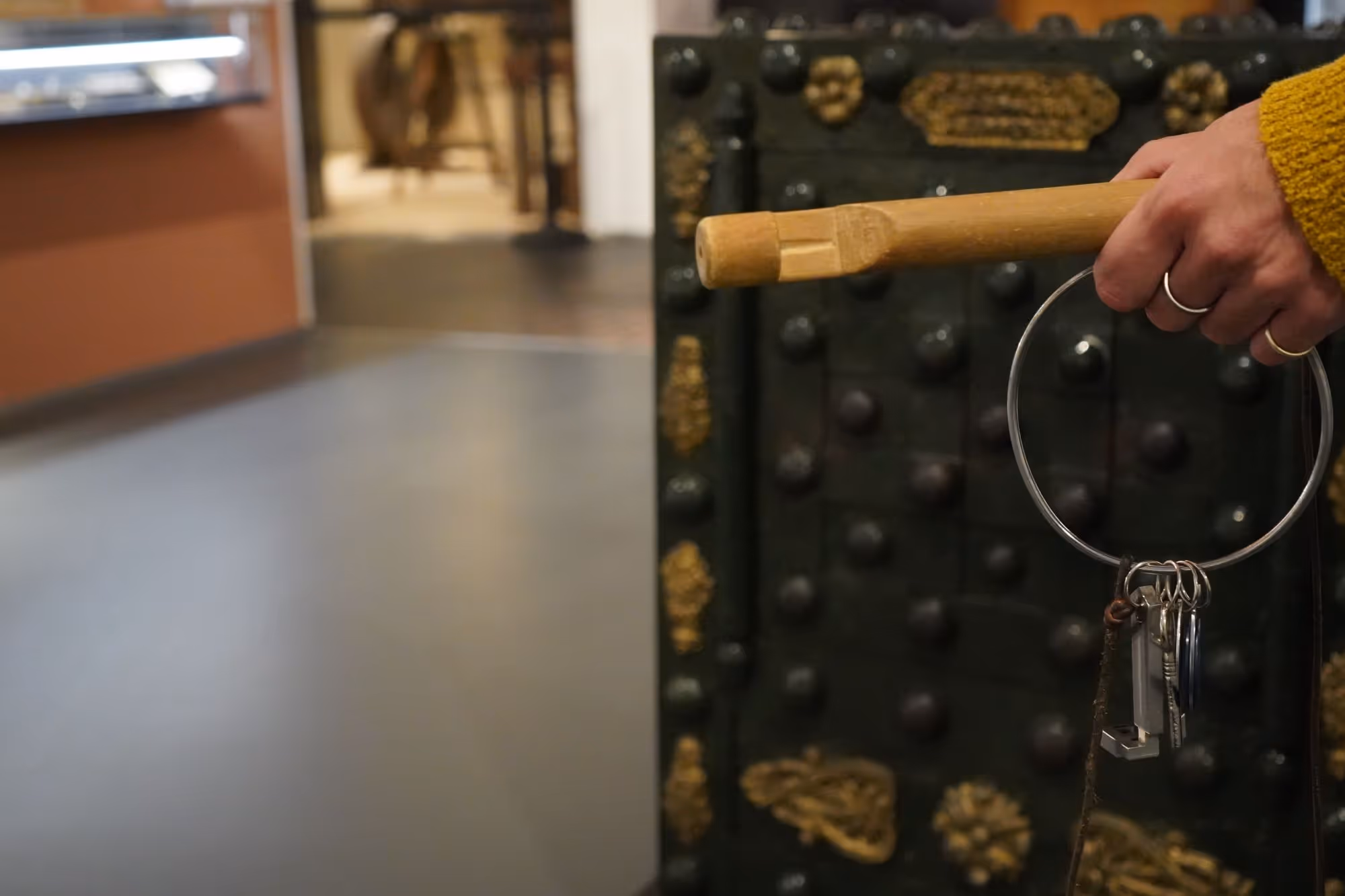 Eine Hand hält einen Schlüssebund mit verschiedenen Schlüsseln vor einem Tresor.