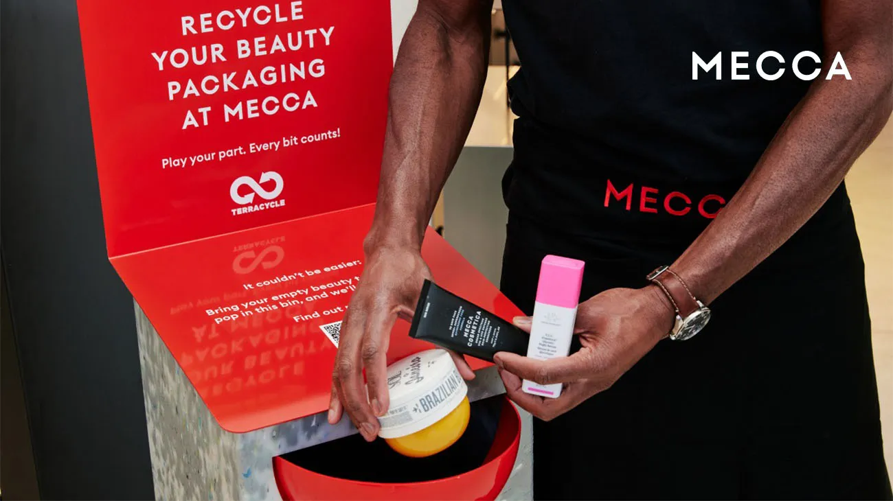 A brightly lit MECCA store interior, featuring a TerraCycle bin for recycling used beauty products.