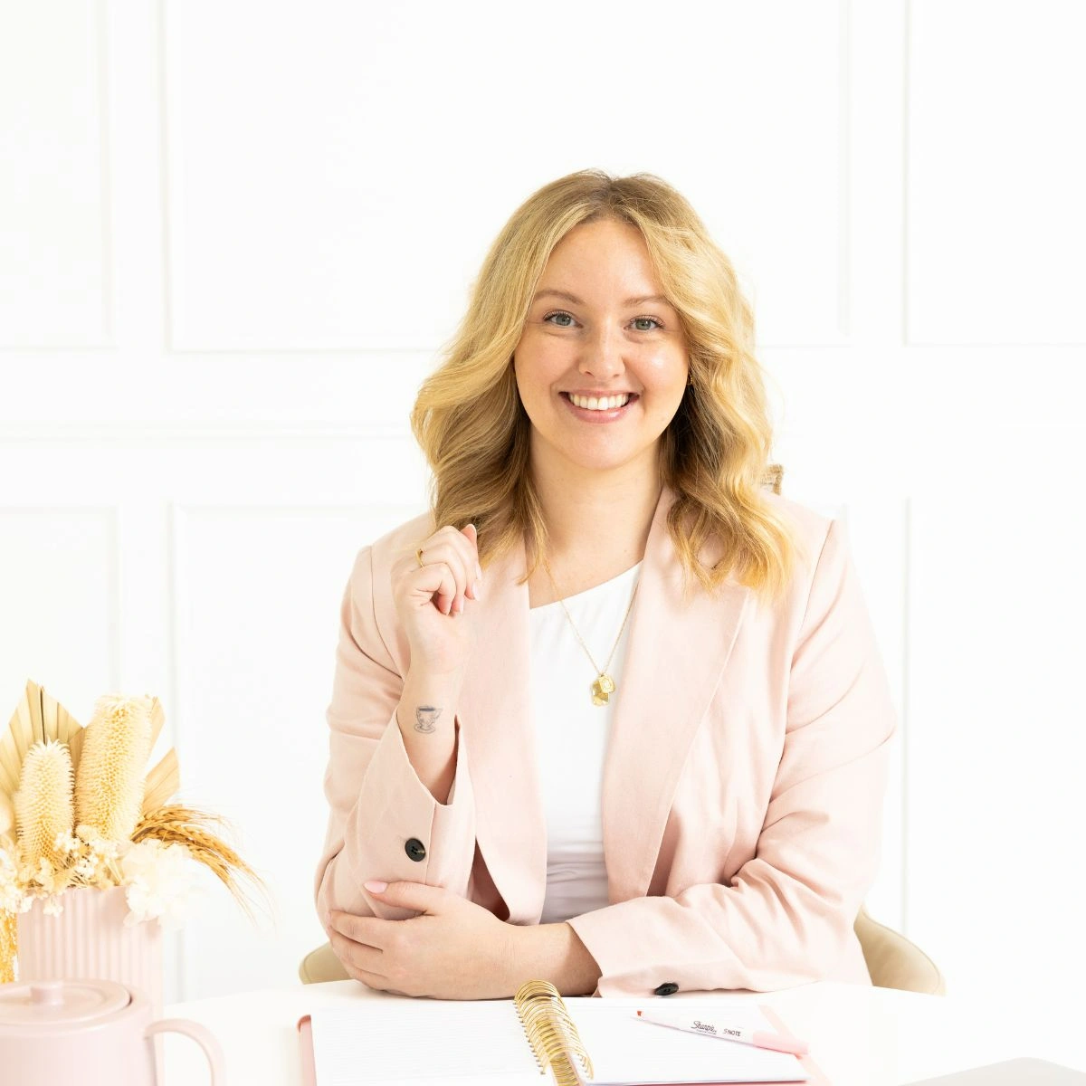 Hayleigh from Hali Helper Studio smiling at desk with notebook and pen