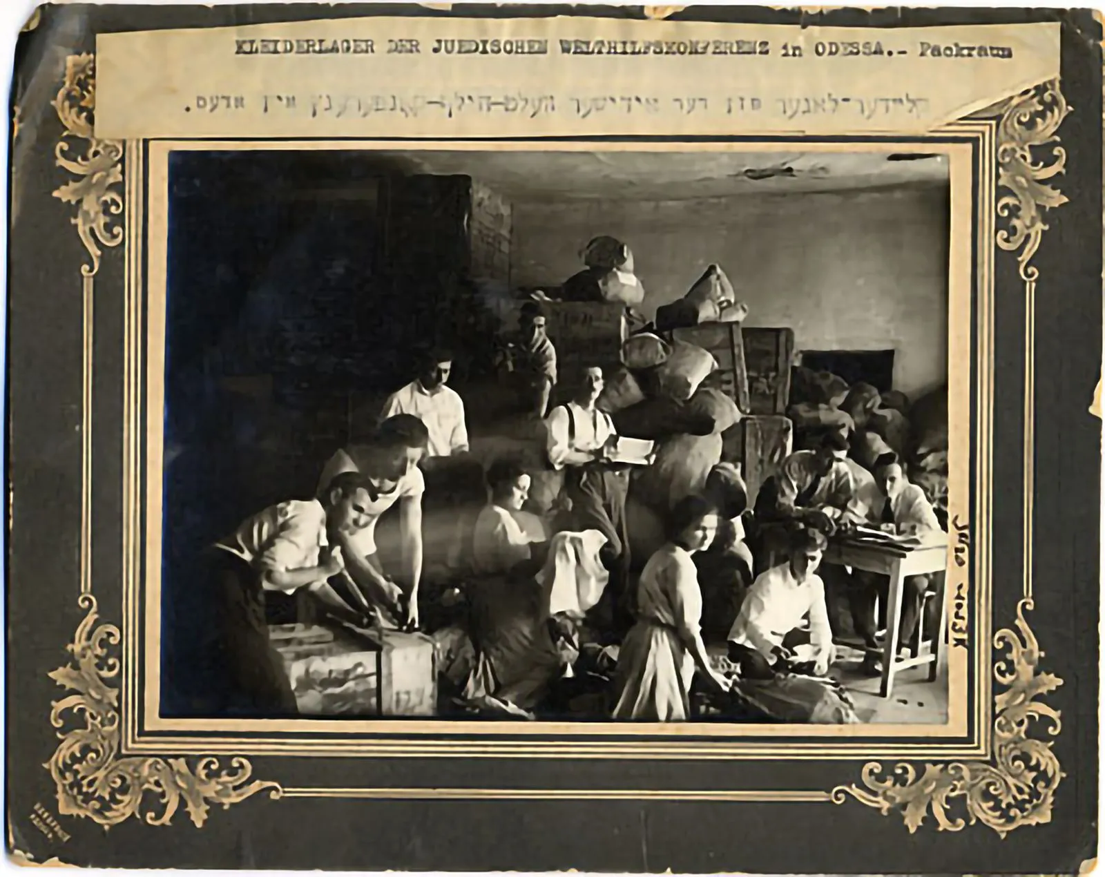Portrait of workers in a Jewish World Aid Conference clothing warehouse opening crates and sorting clothing. (Odessa, 1920's)