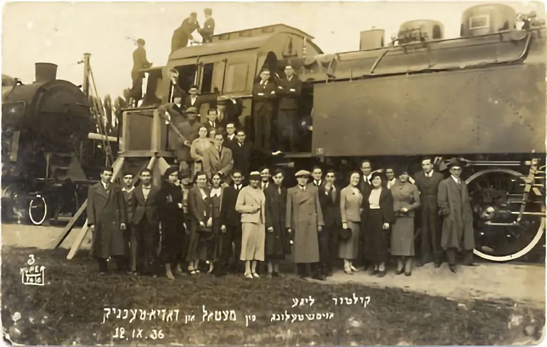 Members of the Kulturlige (the Jewish Workers' Cultural Association) posing in front of a locomotive at a technical exhibition. (Warsaw, 1936)
