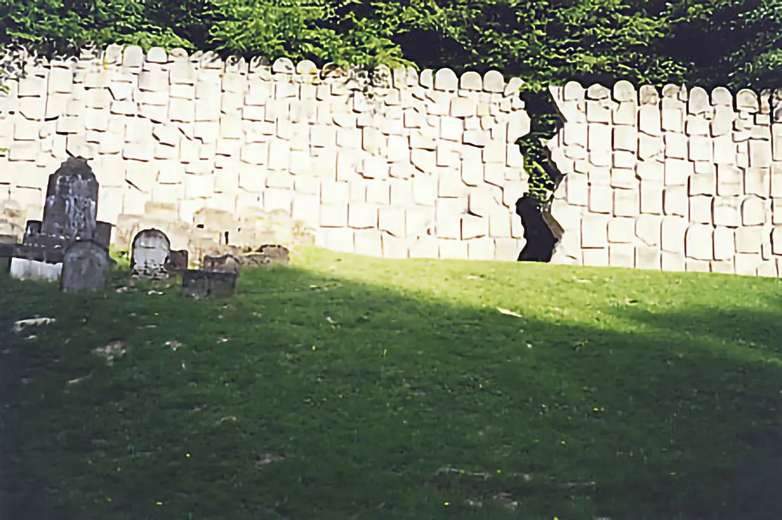 A wall constructed from broken Jewish gravestones in the Jewish cemetery. Photo by Michael Cohen. (Kuzmir, 2001.)