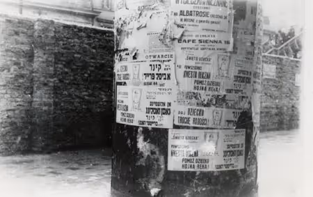 Yiddish and Polish posters in the Warsaw Ghetto. One Yiddish poster reads, "General street assembly: 'Offer the children a little happiness!. Help children with a wide hand (Warsaw, circa 1941).