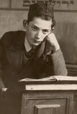 Young talmudic scholar in the Ramailes Yeshiva poses under Hebrew calligraphy that reads "Jerusalem," (Vilna, 1930s). Photo: A. Sapir.