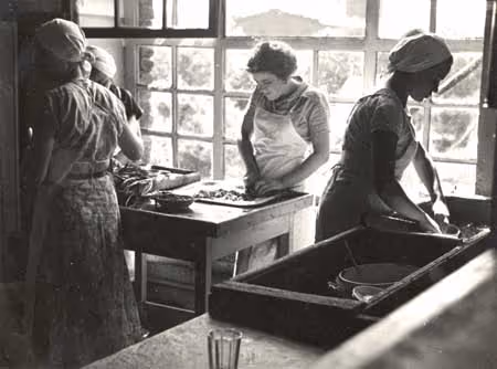 Young women in aprons prepare a meal (Soviet Union, 1930s).
