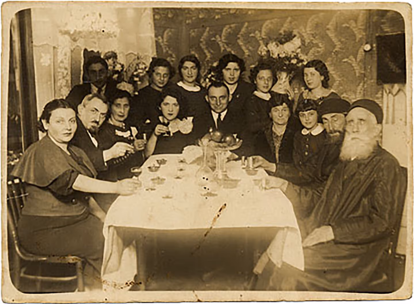Portrait of a family around the table with glasses raised (Zyrardow, Poland, 1934).