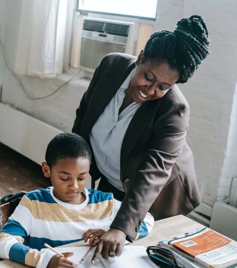 An image of a school teacher providing support for her student during a lesson.