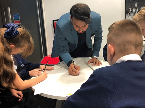 An Employer volunteer works with a group of school students taking part in an Employer Insights activity day. 
