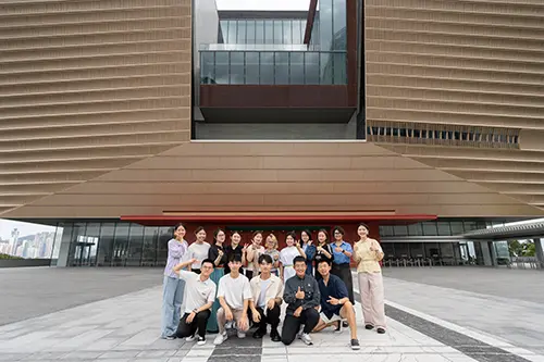 A group of older students working with Ednovators pose in front of their college building