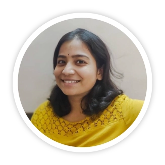 A portrait of Niveditha inside a circular frame with a white border. Niveditha is smiling warmly and is wearing a bright yellow blouse.