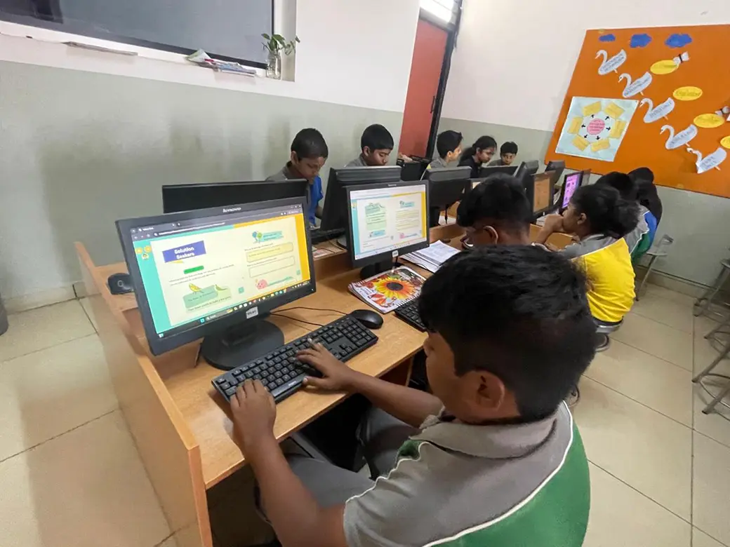 A group of children aged 8-10 sat at a row of computer desks browsing the Yellow Owl magazine.