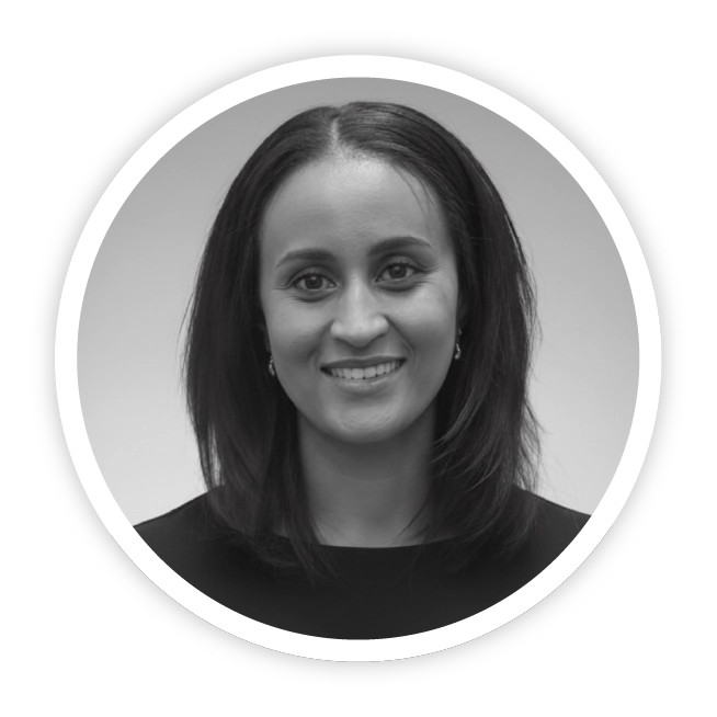 A black and white photo of Sophie Deaville, Head of Programmes at Skills Builder Global. She is a mixed-race British woman wearing a smart black suit-dress a bob haircut and has a warm, kind, confident smile.