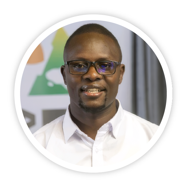 A picture of Collins Otieno from Mukuru Shujaa, Kenya. He is wearing a white shirt and glasses and is smiling calmly.