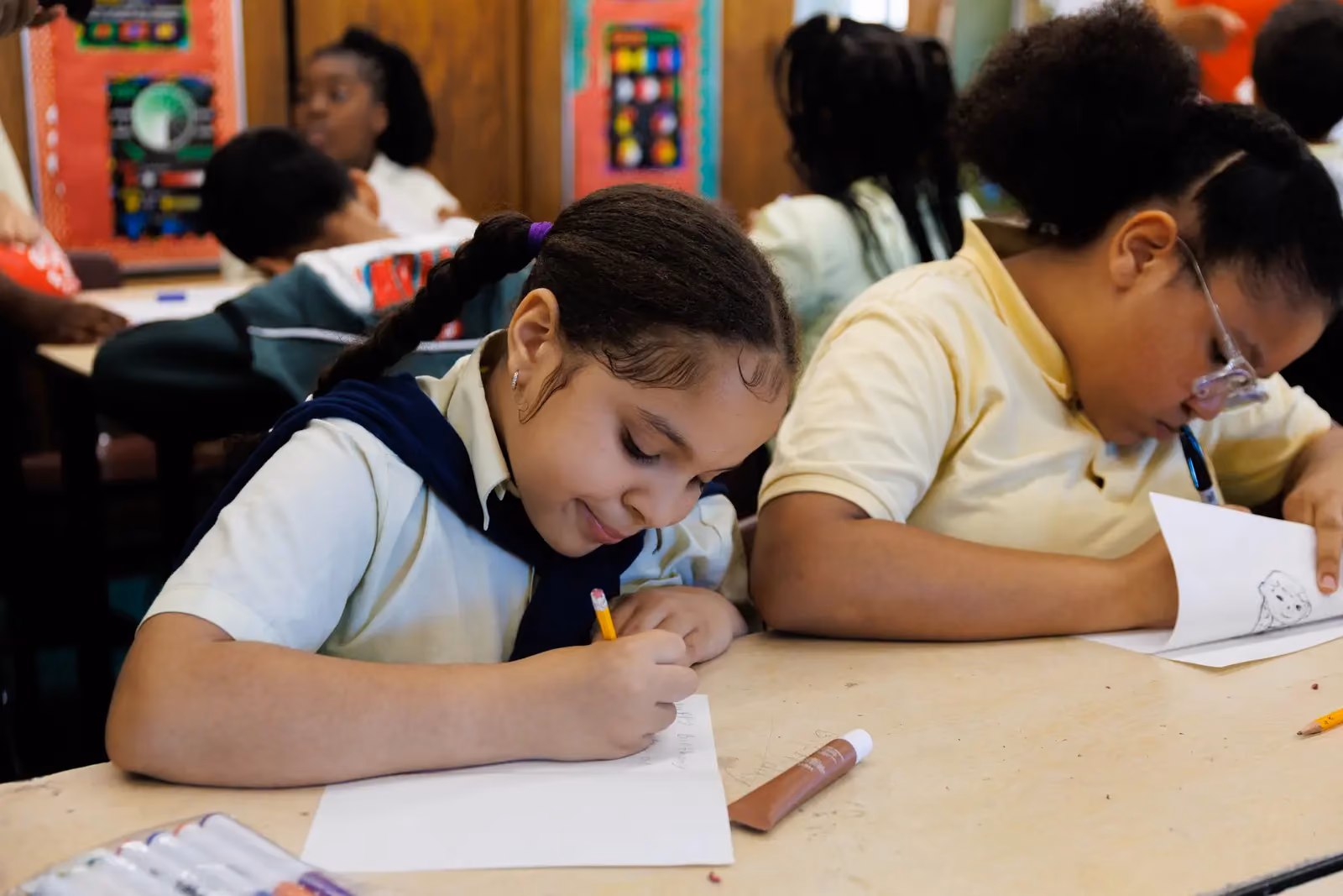 Students writing at desks during a classroom activity