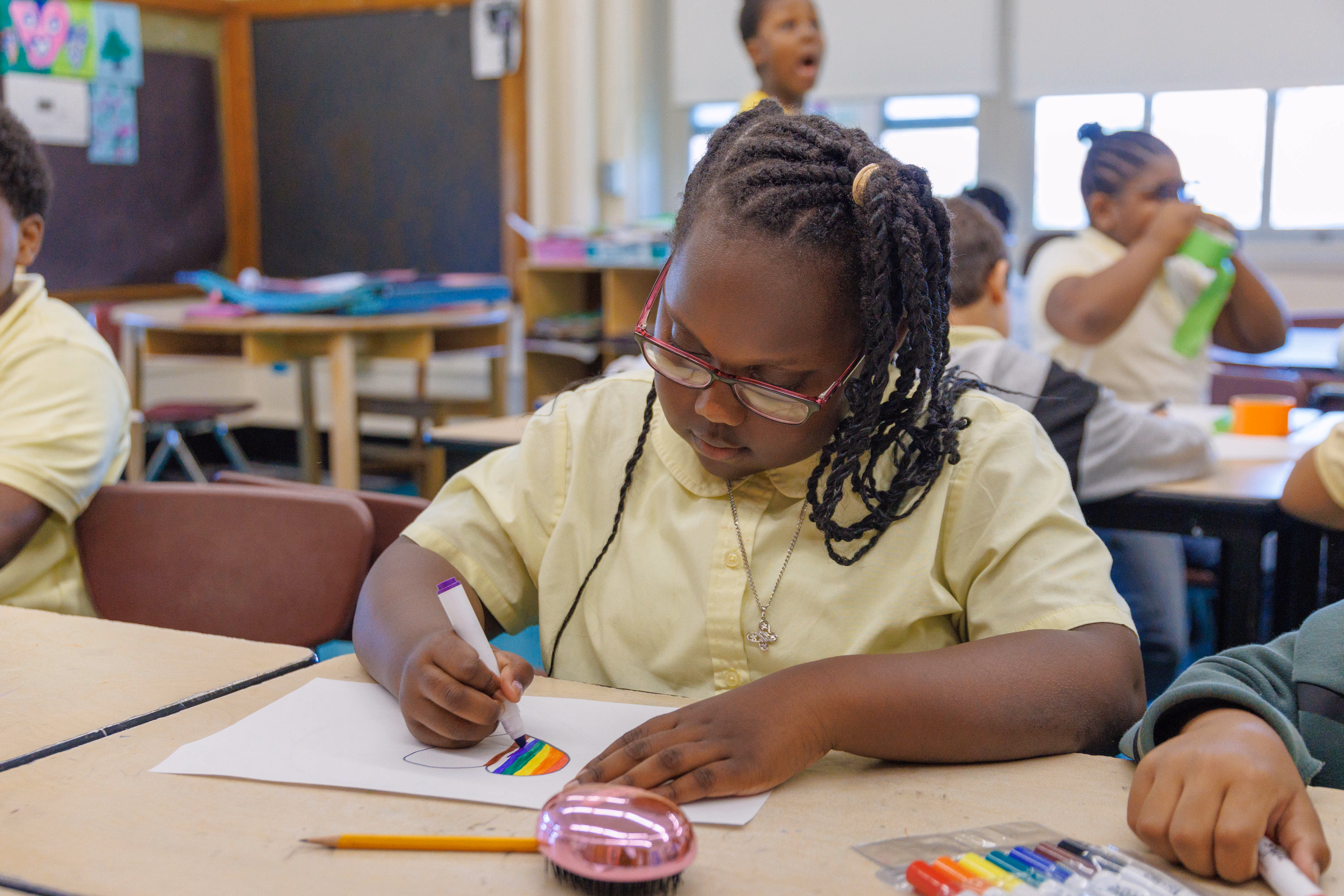 Student coloring a rainbow drawing during art class