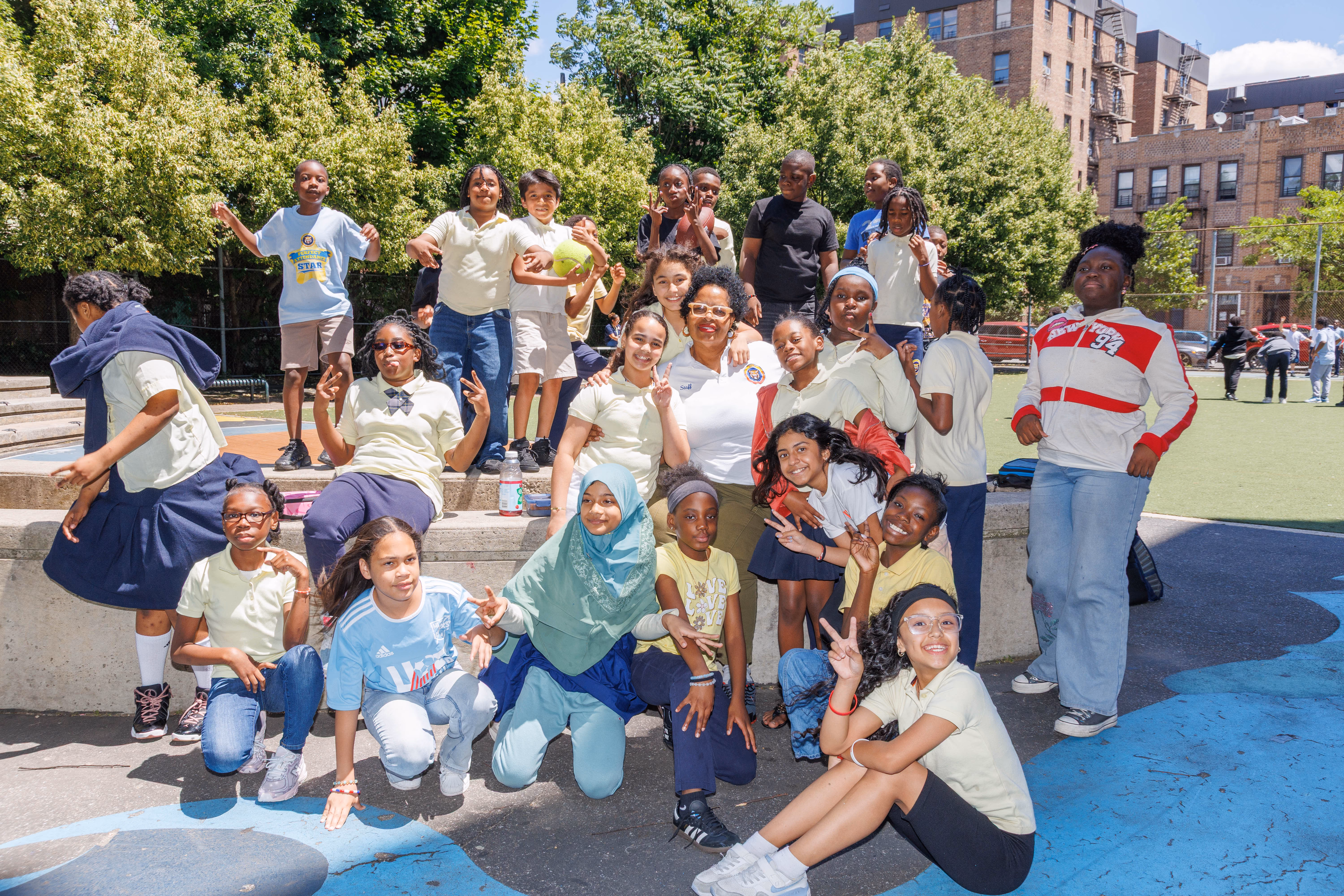 Students and teacher posing together outdoors on school playground