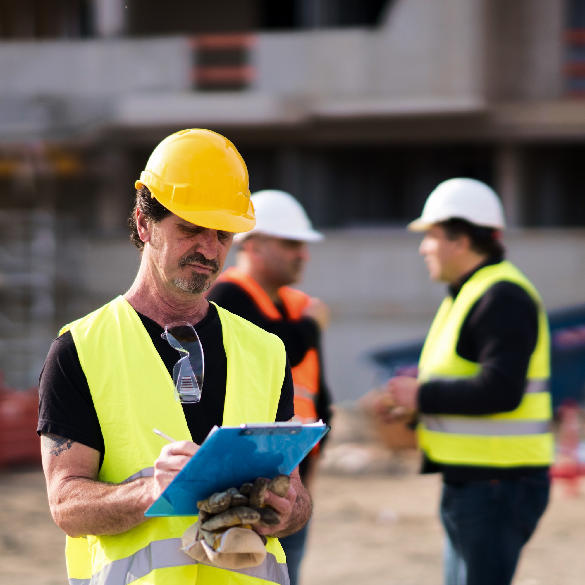 A man in a yellow safety vest holding a clipboard.