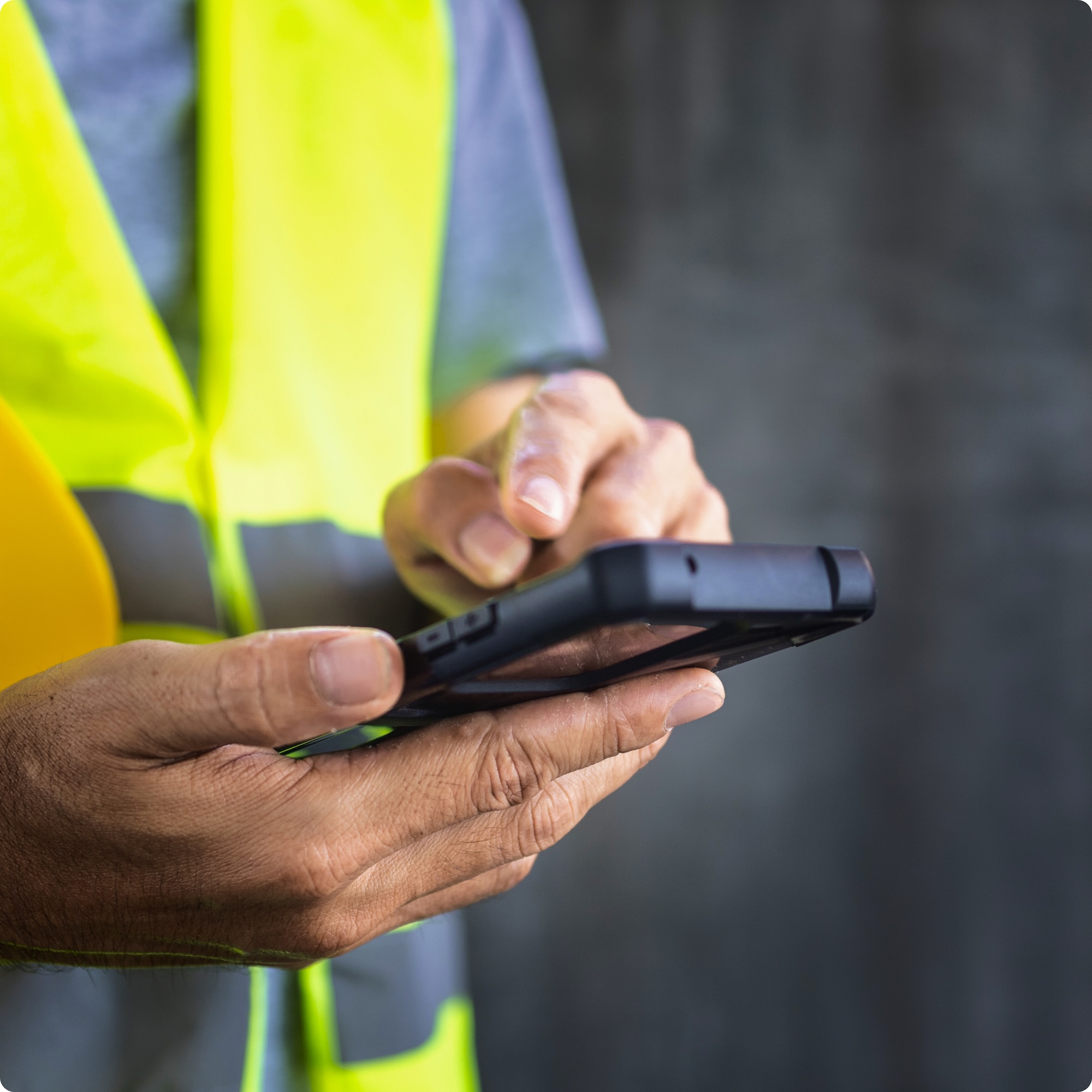 A man in a safety vest holding a cell phone.