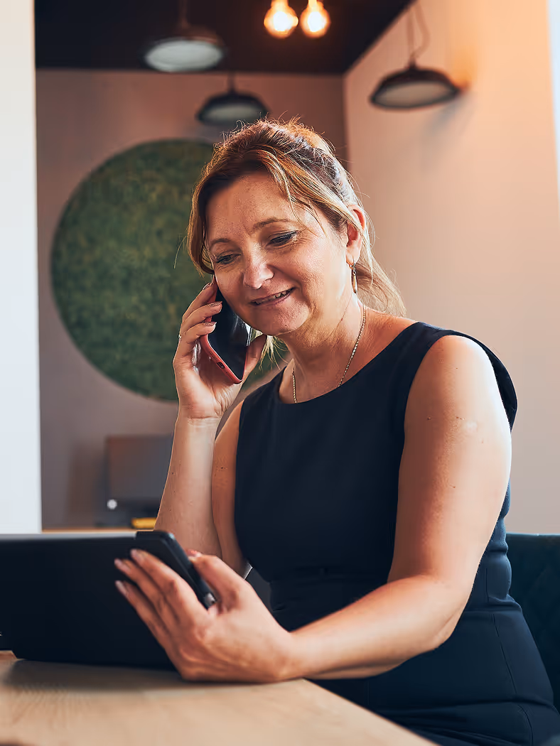A woman sitting at a table talking on a cell phone.