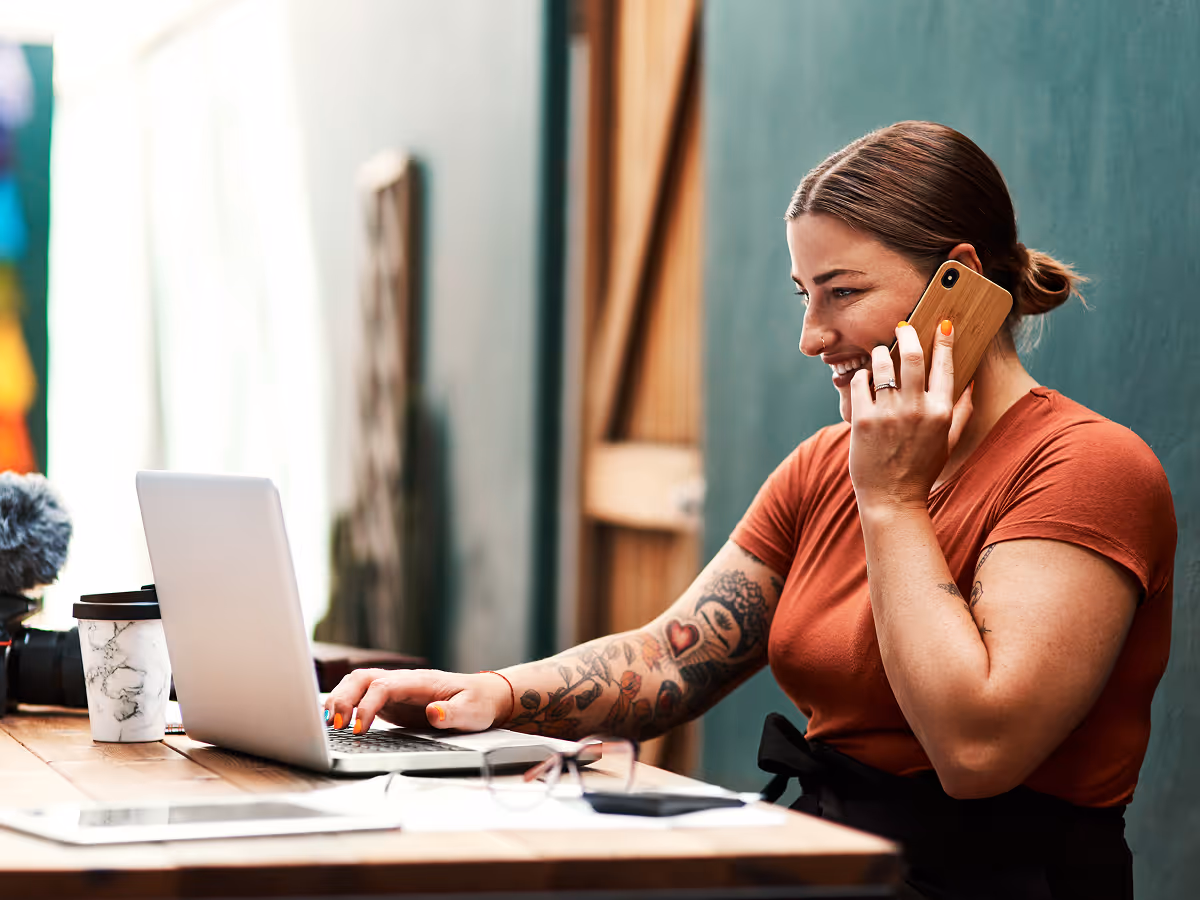 A woman sitting at a table talking on a cell phone.