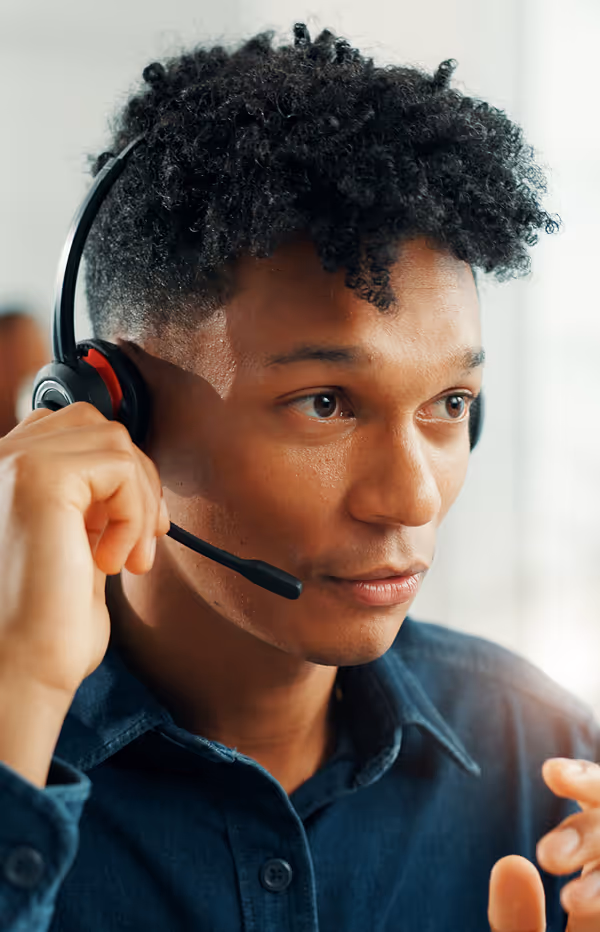 A man wearing a headset and holding a cell phone to his ear.