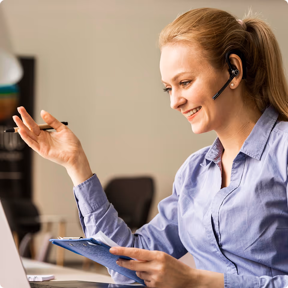 A woman wearing a headset and using a laptop.