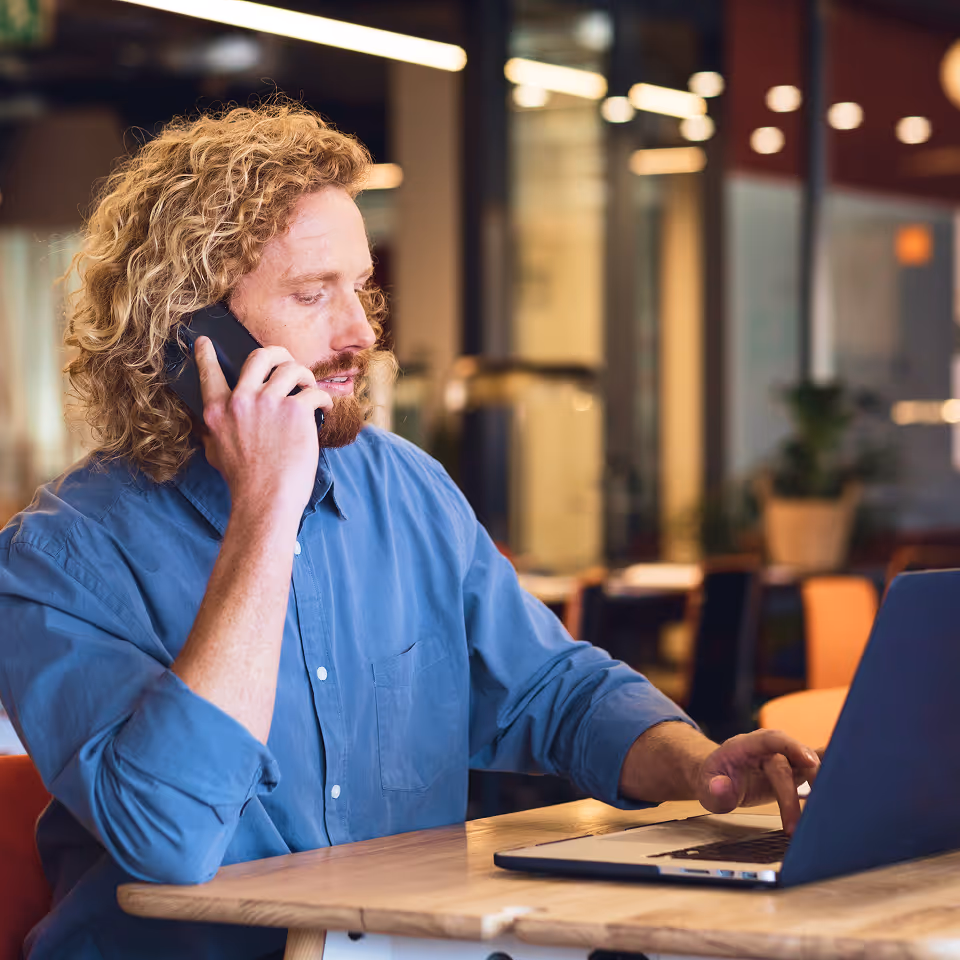 A man sitting at a table using a laptop computer.