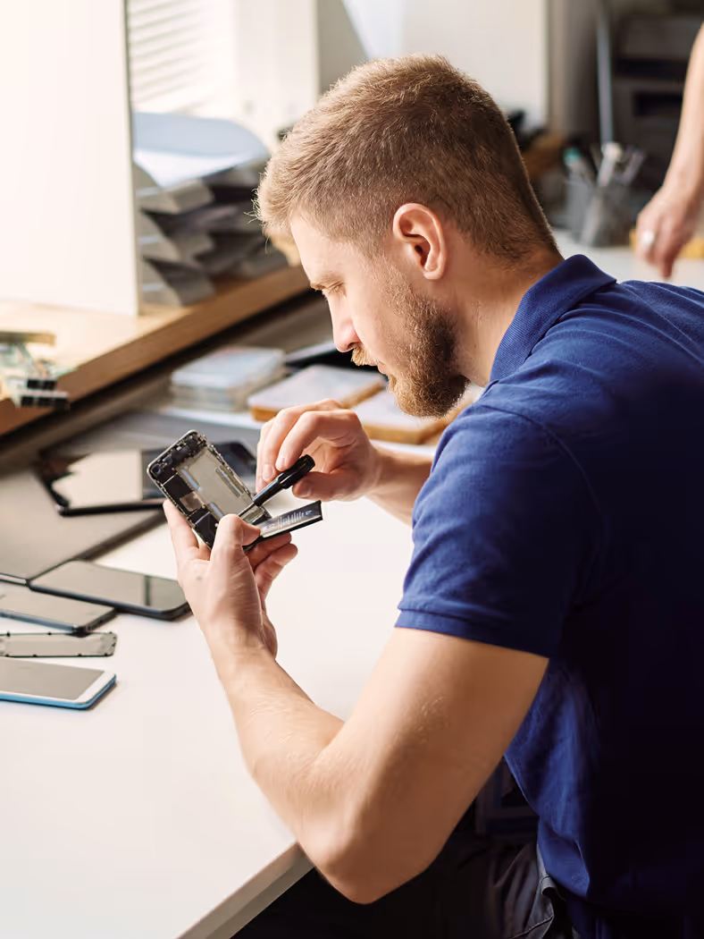 A man sitting at a desk looking at his cell phone.