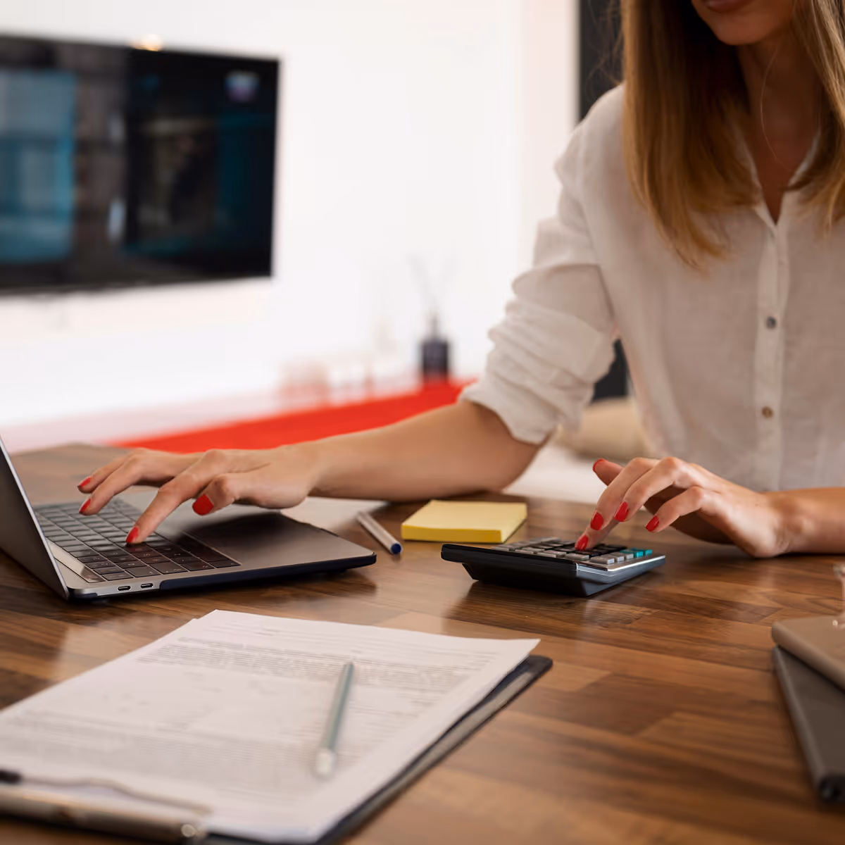A woman sitting at a table with a laptop and calculator.