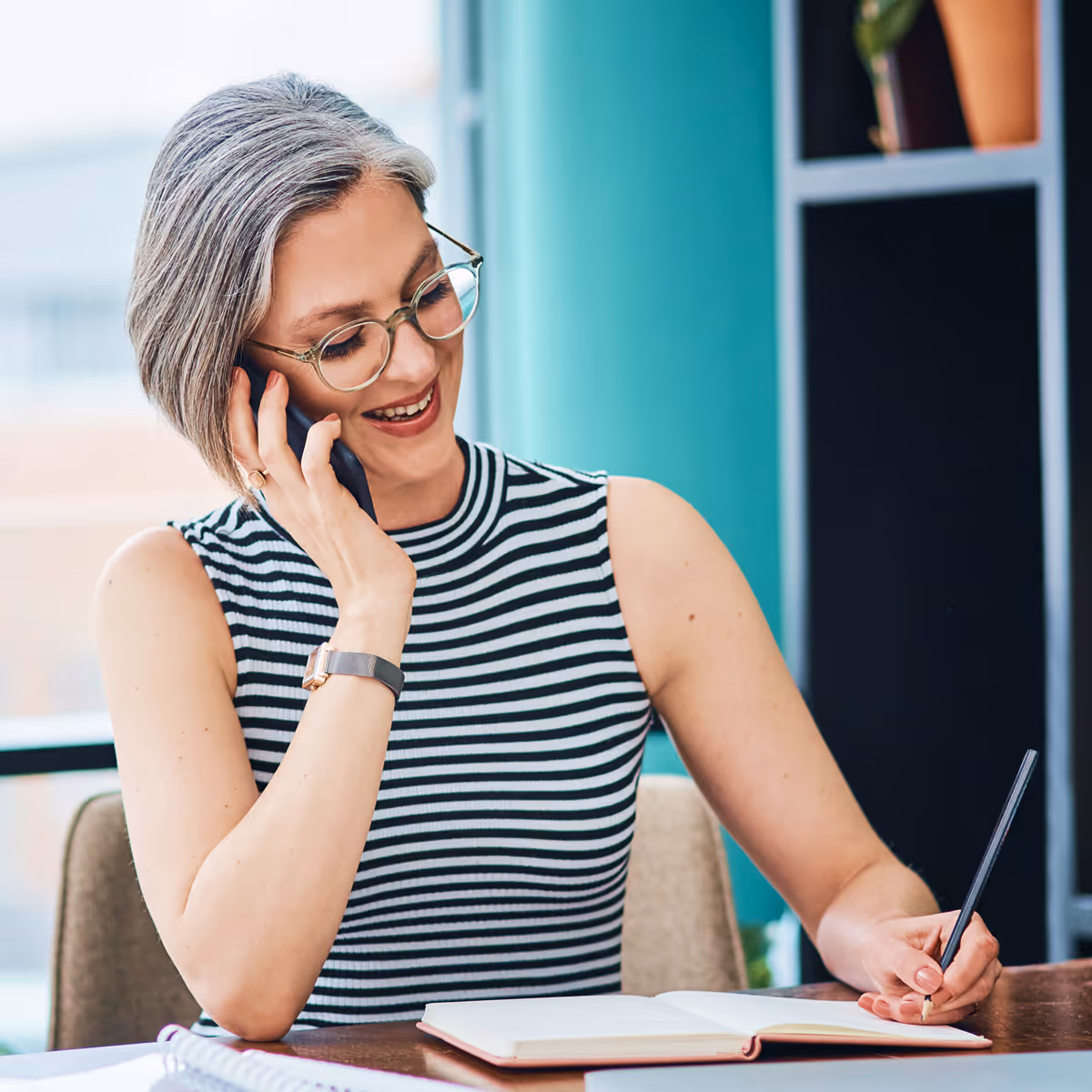 A woman sitting at a table talking on a cell phone.