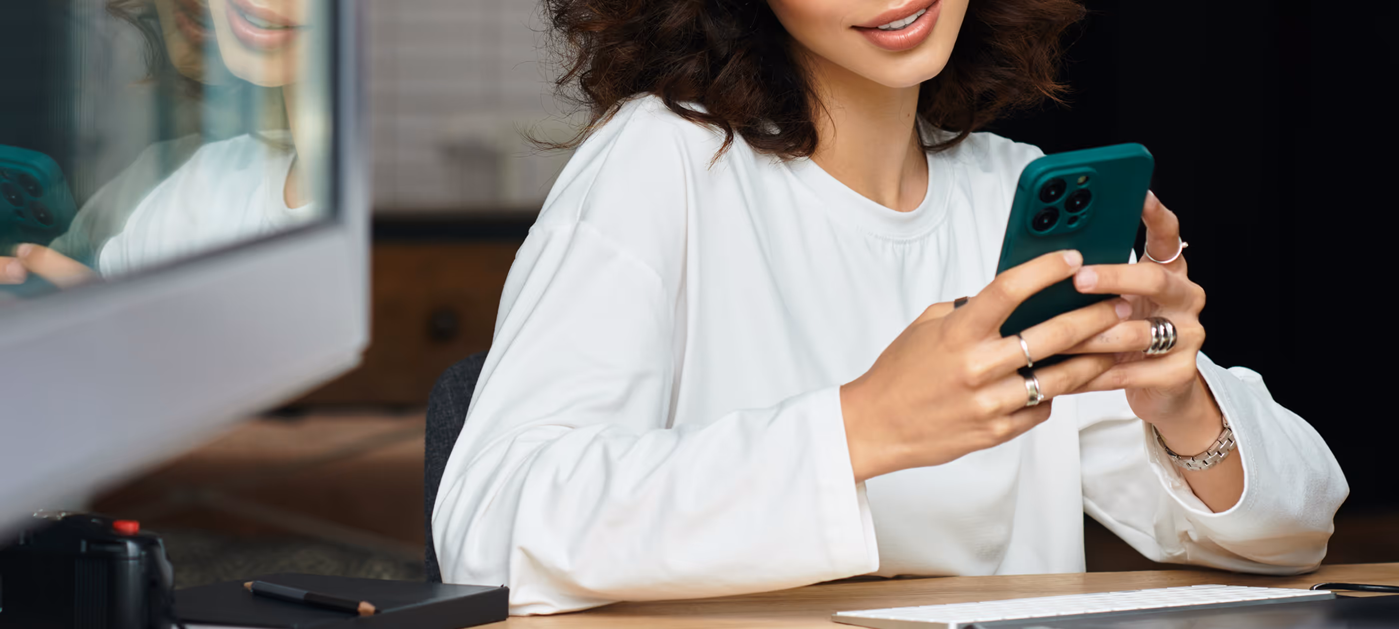 A woman sitting at a table holding a cell phone.