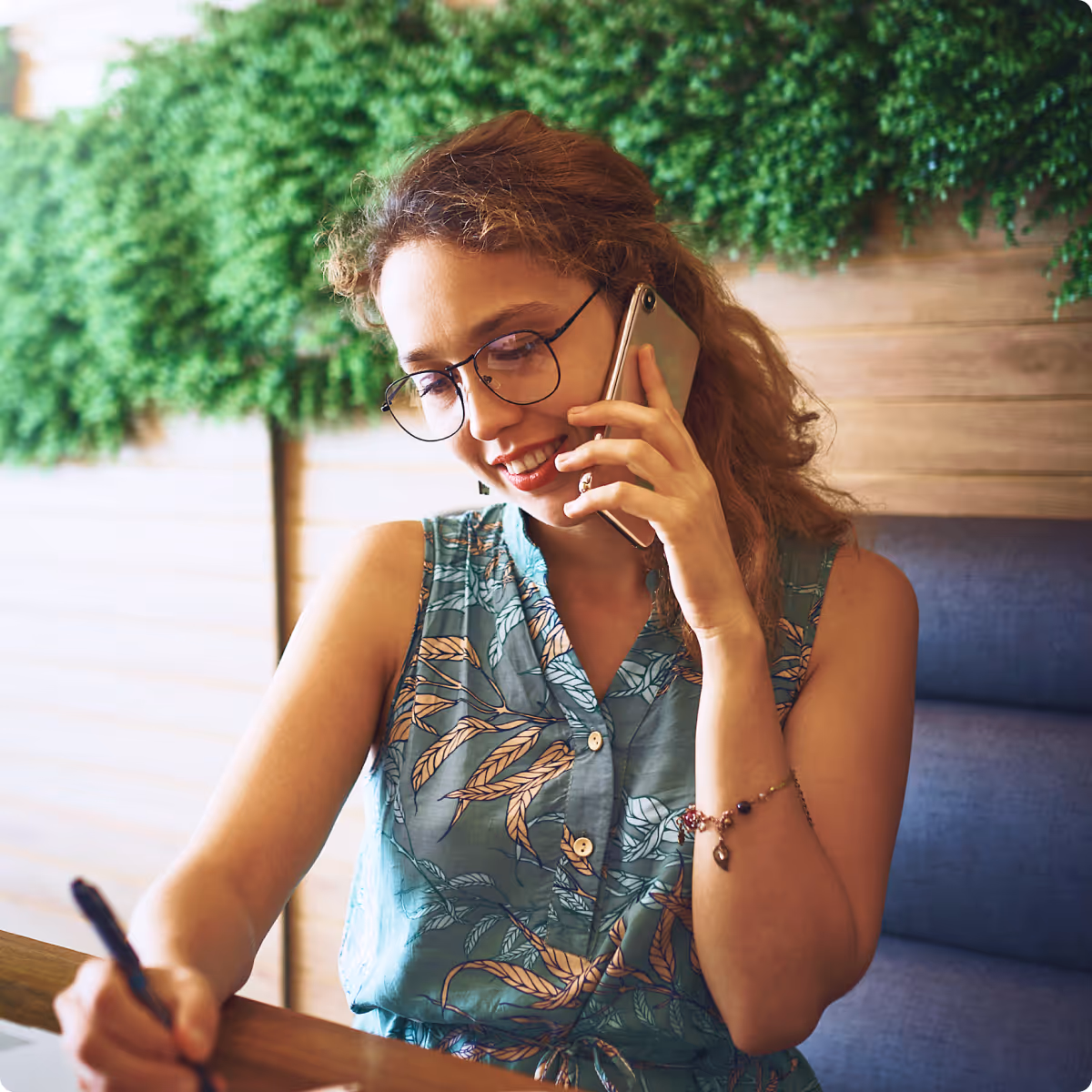 A woman sitting at a table talking on a cell phone.