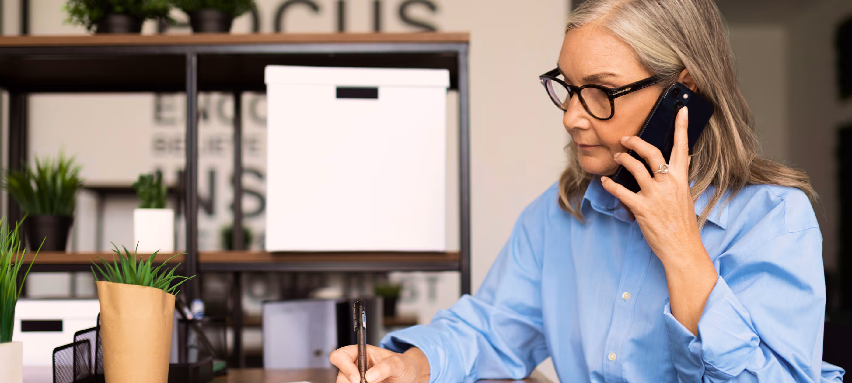 A woman sitting at a desk talking on a cell phone.